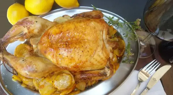 Un capón asado, jugoso y dorado, servido con patatas y limones. ¡Un festín para los sentidos!