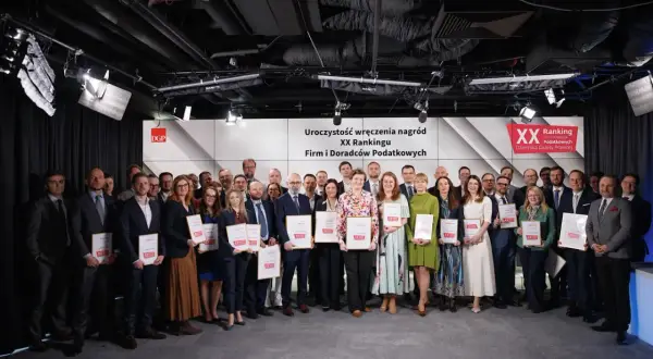 Grupa nagrodzonych osób z dyplomami na tle sceny z logo XX Rankingu Firm i Doradców Podatkowych.