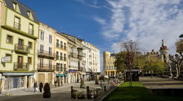 Paseo por el casco antiguo de Ribadeo que ver: fachadas coloridas, balcones de hierro y un cielo azul con nubes.