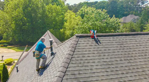 A roofer demonstrates how to shingle a steep roof, using safety gear and a ladder.