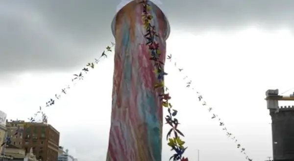Un'installazione colorata, alta e decorata con festoni di fiori. Si immagina di poter toccare il naso di Pulcinella.