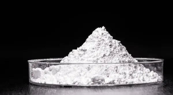 Feiner weißer Pulverberg in einer Petrischale. Dieses Titandioxid ist ein wichtiger Inhaltsstoff in Kosmetikprodukten, z.B. für Sonnenschutz.