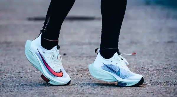 Course sur route avec des chaussures de running blanches dotées d'une plaque carbone.