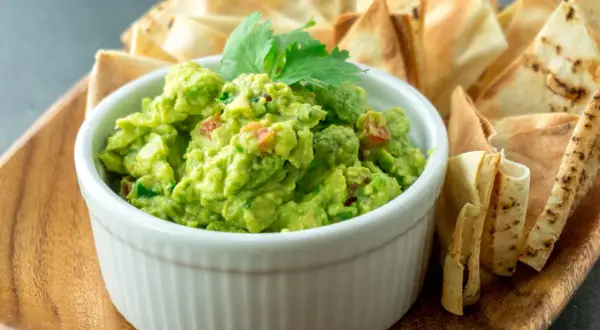 Pyszne guacamole z pomidorami i kolendrą, idealne do szybkiego przygotowania. Podane z chrupiącymi nachos.