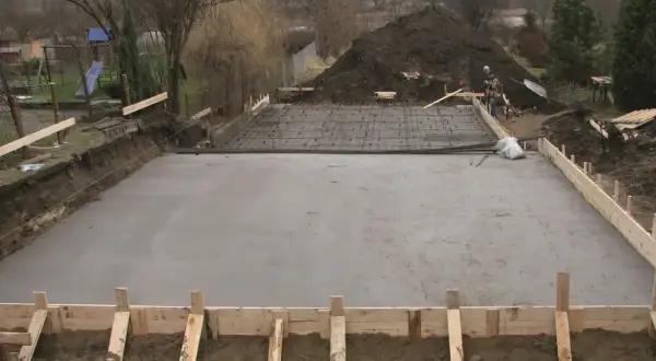 Plac budowy z wylana betonowa płyta fundamentowa i zbrojenie.