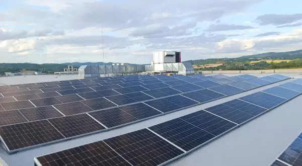 Duże panele fotowoltaiczne na dachu, obok systemów wentylacyjnych i agregatu prądotwórczego, zapewniające niezawodność energetyczną.