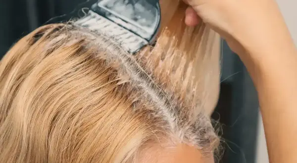 Aplikacja produktu do rozjaśniania włosów na blond. Pędzel równomiernie rozprowadza mieszankę na pasmach.