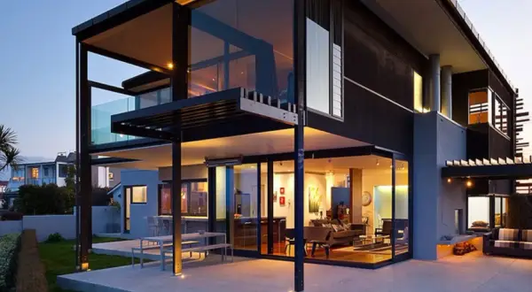 Moderna casa prefabricada diseño, con amplios ventanales y terrazas, iluminada al atardecer.