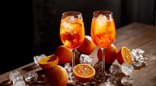 Dwa kieliszki Aperol Spritz z lodem i pomarańczą. Idealne na letnie popołudnie, by poczuć włoskie aperitivo i jego procenty.