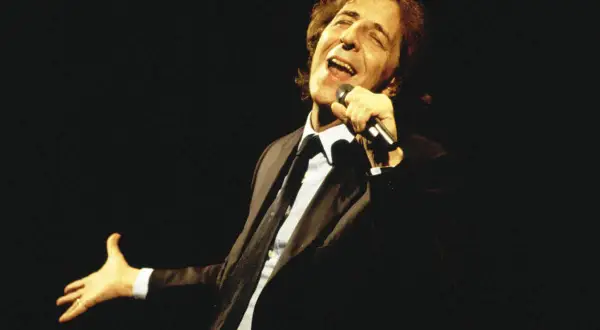 Giorgio Gaber canta con passione, la sua voce risuona come nei testi de "Il Conformista", un'icona della musica italiana.