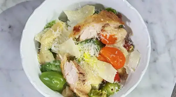 En härlig caesarsallad med kyckling, parmesan och krutonger, generöst täckt med krämig caesarsallad dressing.