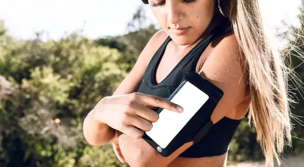 Une coureuse ajuste son téléphone dans un brassard, une solution pratique pour savoir où mettre son téléphone quand on court.