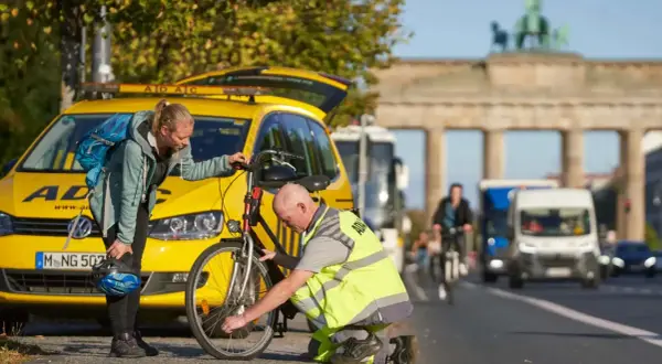 ADAC-Mitarbeiter hilft Frau bei einer **ADAC Fahrradpanne** vor dem Brandenburger Tor.