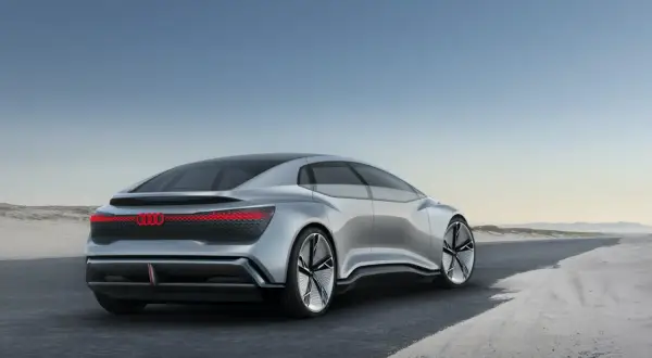 Srebrny Audi A9, futurystyczny koncept, jedzie po pustej drodze.