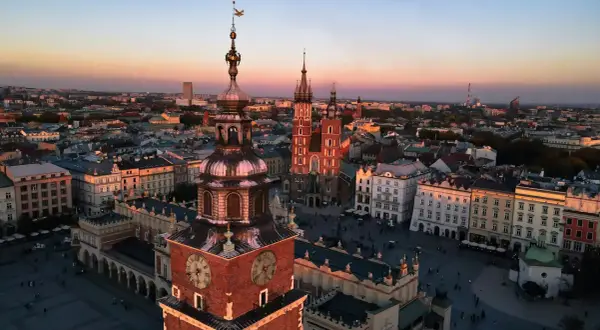 Zachód słońca nad Rynkiem Głównym w Krakowie. Widać wieżę Ratuszową i Kościół Mariacki, ikoniczne kraków zabytki.