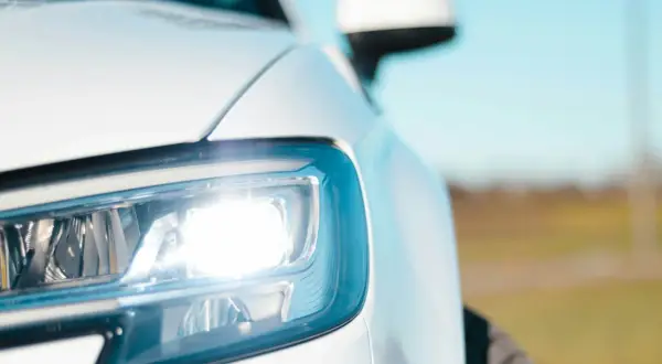 Biały Ford Transit z włączonymi światłami pozycyjnymi. Bezpieczniki świateł pozycyjnych są kluczowe dla sprawnego działania oświetlenia.