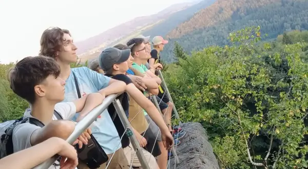 Grupa młodych ludzi podziwia widok z góry. To właśnie jest co to trekking – podróżowanie pieszo przez góry, odkrywanie piękna natury.