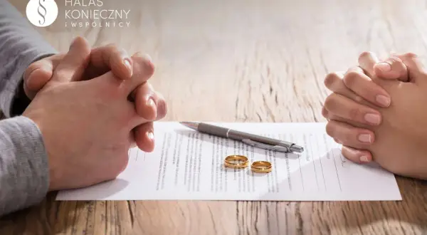 Dwie pary rąk, dokument, długopis i obrączki ślubne na drewnianym stole.