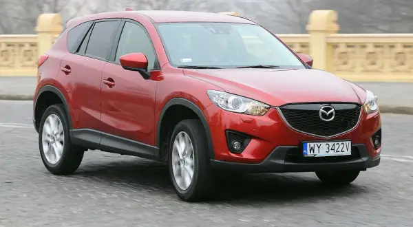 Czerwona Mazda CX-5 na drodze, z widocznym grillem i tablicą rejestracyjną.