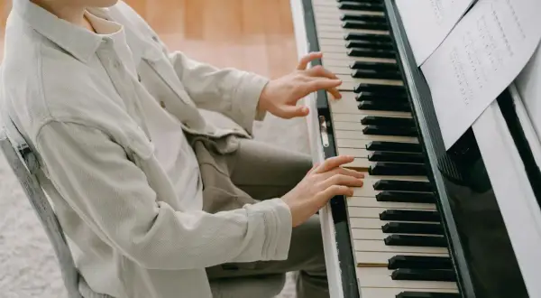 Chłopiec ćwiczy wprawkę dla pianisty, skupiony na nutach.