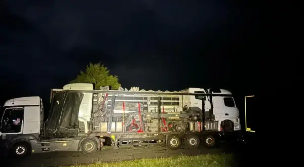 Nocą na poboczu stoi nietypowy pojazd nienormatywny, przewożący elementy maszyn.