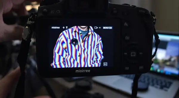 Na ekranie aparatu widać koszulę w tęczowe paski, na której widoczne są artefakty cyfrowe. To przykład, jak wygląda aliasing co to jest.