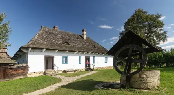 Skansen Sanok: tradycyjna chata i studnia. Idealne miejsce na letnie imprezy i spacery po historii.