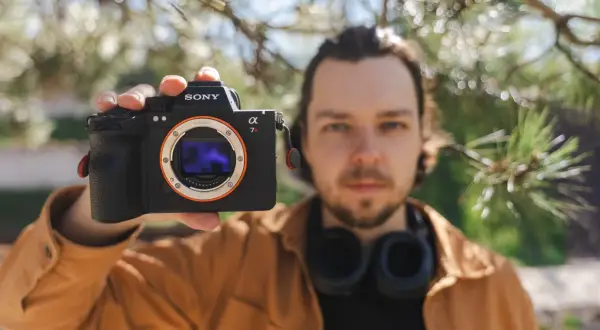 Mężczyzna prezentuje aparat Sony a7riv z obiektywem E-mount.