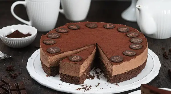 Schokoladentorte mit Mousse und Kakao bestäubt, dekoriert mit Schokoladensternen. Ein Stück ist herausgeschnitten. Perfekt für ein Schokotorte Rezept.