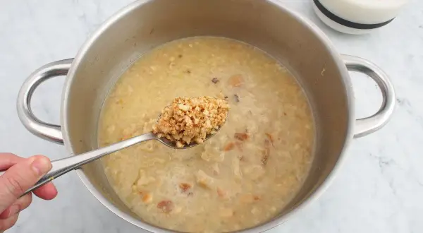 Cuchara con trozos de almendras listas para añadir a la salsa en la olla.