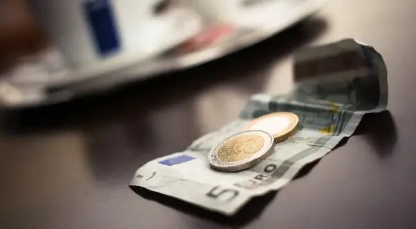 Na stole leży banknot 5 euro i monety. To waluta w Grecji, idealna na kawę.