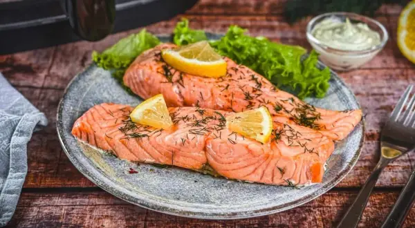 Zwei saftige Lachsfilets, perfekt im Airfryer zubereitet, garniert mit Zitrone und Dill. Dazu knackiger Salat und eine cremige Sauce.