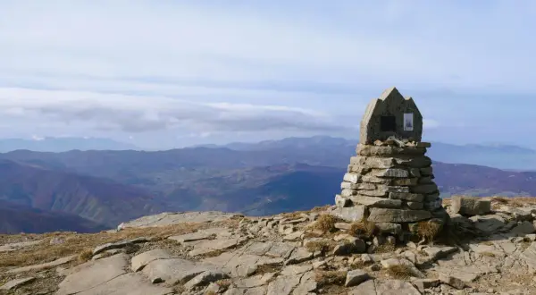 Cairn in pietra sulla cima del monte più alto Emilia Romagna, con vista panoramica sulle colline sottostanti.