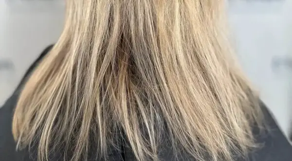 Nahaufnahme von schlecht blondierten Haaren mit ungleichmäßigen Blondtönen und sichtbaren Ansätzen.