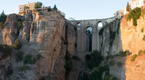 Impresionante puente de piedra sobre un profundo tajo, ideal para rutas por Ronda. Edificios se asoman al abismo.