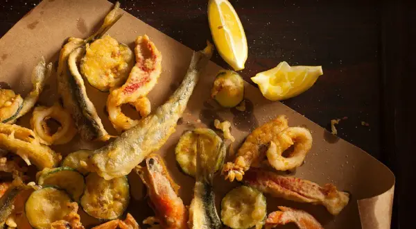 Fritto misto di mare e verdure, croccante e dorato, perfetto con il suo olio per frittura di pesce. Limone a spicchi per un tocco fresco.
