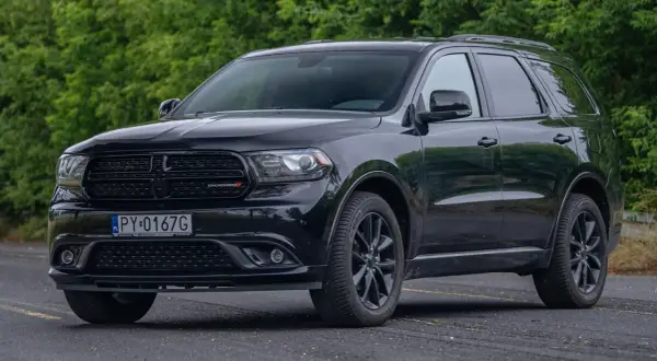 Czarny Dodge Durango 3.6, lśniący na tle zieleni, gotowy na każdą podróż.