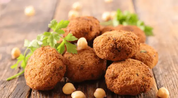 Polpette dorate e croccanti, perfette polpette senza uova, guarnite con prezzemolo fresco e ceci su un tagliere di legno.