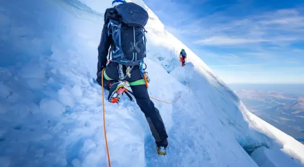 Bergsteiger auf dem Mont Blanc Normalweg, gesichert durch ein Seil, steigen über eisige Hänge.