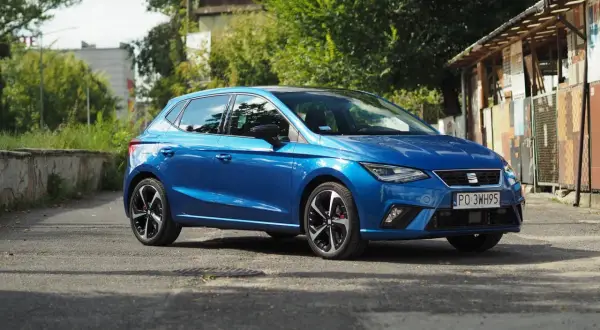 Niebieski Seat Ibiza na tle zieleni i budynków. Poznaj jego seat ibiza dane techniczne.