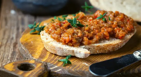 Pyszna pasta z bakłażana na chrupiącym pieczywie, ozdobiona świeżymi ziołami. Idealna na przekąskę.
