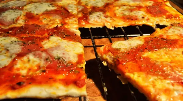 Pyszna pizza na cienkim cieście, z ciągnącym się serem i aromatycznym sosem pomidorowym, prosto z pieca.