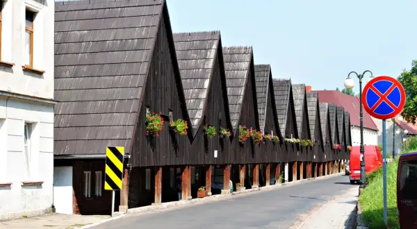Rząd drewnianych domów z charakterystycznymi spiczastymi dachami i kwitnącymi balkonami. Chełmsko Śląskie atrakcje zachwycają unikalną architekturą.