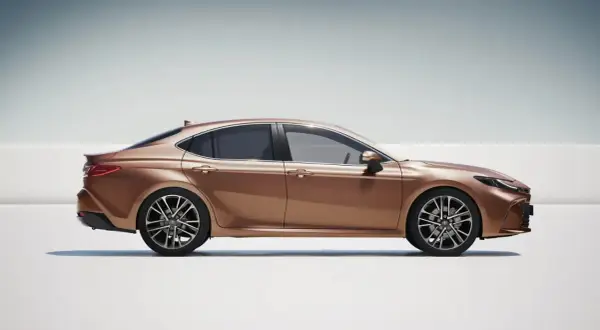 Elegancka, brązowa Toyota Camry używana, prezentująca swój dynamiczny profil na jasnym tle.
