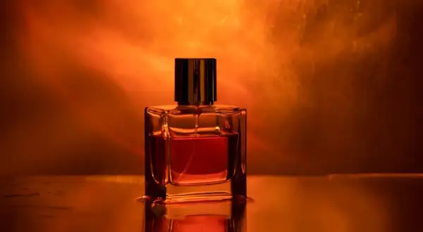 Szklana buteleczka perfum z bursztynowym płynem, emanująca ciepłym, zmysłowym amber zapach.