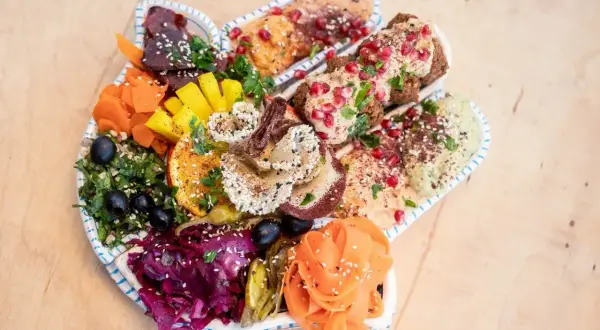 Kolorowy talerz pełen hummusów, falafeli i warzyw. Idealna propozycja dla szukających restauracji wegańskiej w Gdańsku.