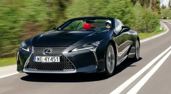 Czarny kabriolet Lexus LC 500 z czerwonym wnętrzem sunie po krętej drodze, zapewniając czystą przyjemność z jazdy i poczucie lexus relax.