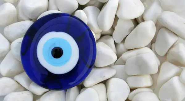Niebieskie oko proroka znaczenie - amulet chroniący przed złym spojrzeniem, leżący na białych kamieniach.