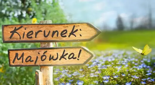 Drewniany drogowskaz "Kierunek: Majówka!" na tle kwitnącej łąki i latającego motyla. Idealny na majówkę 2026!