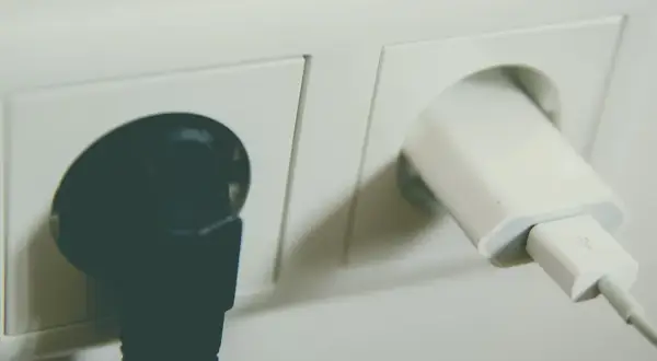 Dwa gniazdka elektryczne: jedno z czarną wtyczką, drugie z białą ładowarką USB. Sprawdź montaż gniazdka cena.